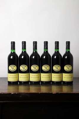 six bouteilles de vin sont posées sur une table devant un mur blanc