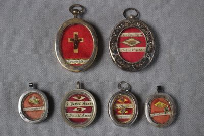plusieurs pendentifs en verre argenté et rouge disposés sur un fond gris