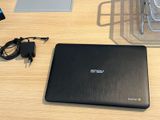 un ordinateur portable posé sur un bureau, avec son chargeur