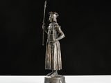 a silver statue of a man holding a sword on top of a wooden base