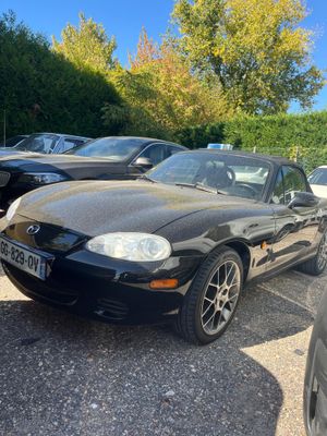 a black car parked in a parking lot next to other cars