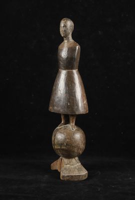 une statue en bois représentant une femme debout au sommet d'une boule