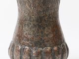 un vase brun posé sur une surface blanche