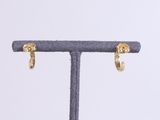 a close up of a pair of gold earrings on a stand