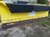 a large yellow snow plow sitting in front of a building