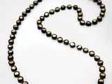 a close up of a black and gold beaded necklace on a white surface