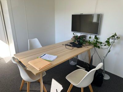 des tables et des chaises dans une pièce où est accrochée au mur une télévision à écran plat