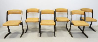 four yellow chairs are lined up against a white wall