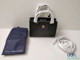 un sac à main noir et un sac bleu posés sur une table blanche