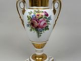 a white vase with gold trim and flowers on it