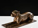 a bronze statue of a dog laying on top of a white surface