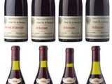 six bottles of wine are lined up on a white surface