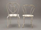 pair of white wrought chairs with arms and backrests