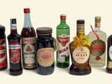 de nombreuses bouteilles d'alcool de toutes sortes alignées sur une surface blanche