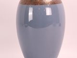 un vase bleu à bord doré posé sur une surface blanche