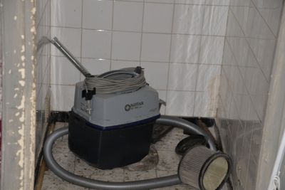 an image of a dirty bathroom with a vacuum in the corner
