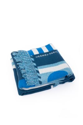 the blue and white striped blanket is folded up on a white surface