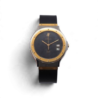 l'image d'une montre noire et or sur une surface blanche