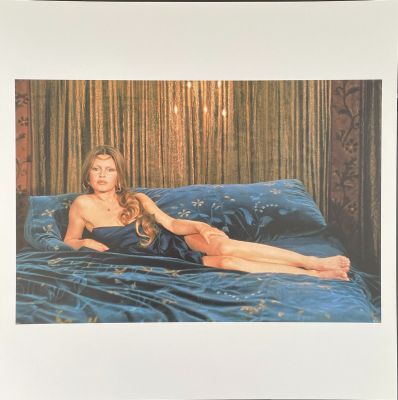a picture of a woman laying on a bed in a blue dress