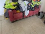 a red couch with a lot of clothes on it