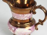 a pink and gold vase sitting on a white table