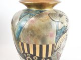 a vase with a painting on it sitting on a white surface