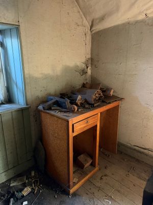 un petit bureau dans un coin d'une pièce dotée d'une fenêtre