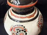 a black and white vase with orange designs on it
