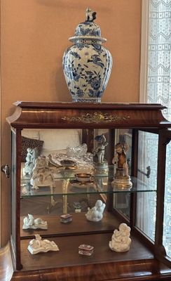 a display case with a vase on top of it in a living room