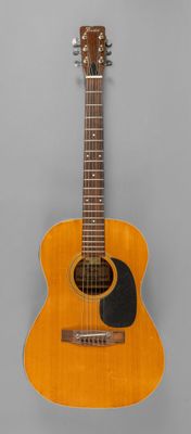 une vieille guitare acoustique posée sur une surface grise