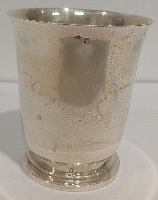 une tasse en argent posée sur une surface blanche