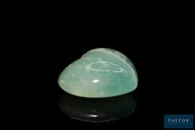 a close up of a green jade heart shaped object on a black surface