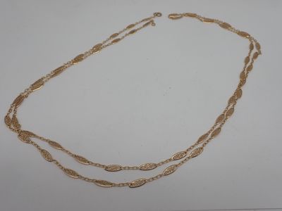 gros plan d'un collier en or sur une surface blanche