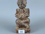 un gros plan sur une figurine représentant une personne assise sur un tabouret