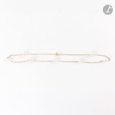un bracelet en chaîne dorée orné de perles sur fond blanc