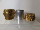three gold vases sitting on a clear shelf