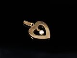 a close up of a gold heart pendant with a pearl in the middle