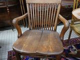 a wooden chair sitting in a room with a painting on the wall