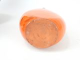 an orange vase sitting on a white surface next to a cup