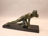 statue en bronze représentant une femme penchée en avant, posée sur un socle noir