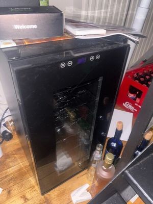 a wine cooler sitting on a wooden table next to a computer