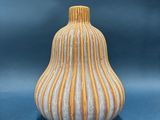 yellow and white striped vase sitting on a blue surface
