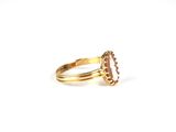 a close up of a gold ring with a pink stone