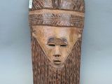 gros plan d'un masque en bois sur une surface grise