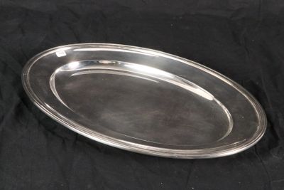 an oval silver plate with a handle on a black background