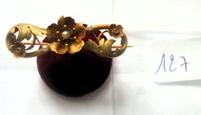 une broche en or ornée de fleurs, présentée dans un écrin en velours rouge