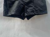 a black shorts hanging on a hanger on a white sheet