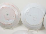 three white plates with red and green designs on them sitting on a table