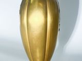 a gold vase sitting on a white surface with a shadow