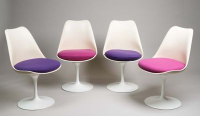 quatre chaises « Tulip » avec des coussins violets, alignées sur une surface blanche